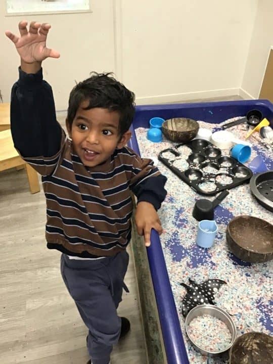 Aotea porirua child waving at sensory tray
