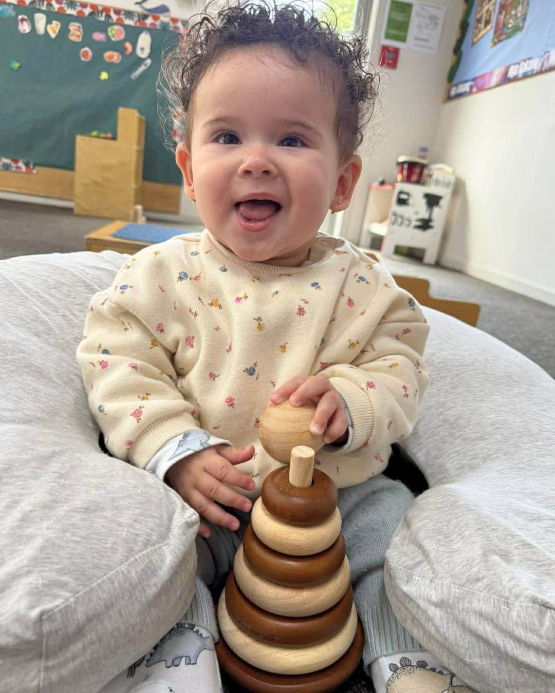 A happy child playing with a wooden Montessori stacking toy at Li'l Champs